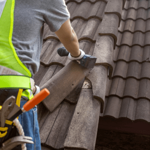 Worker man replace tile of the old roof. Common roof repairs.