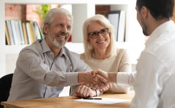 Happy old couple handshake meeting claims specialist